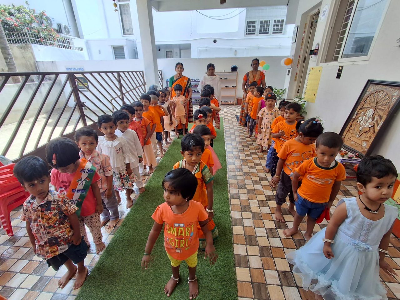 Children in orange walking happily in a line along the school corridor